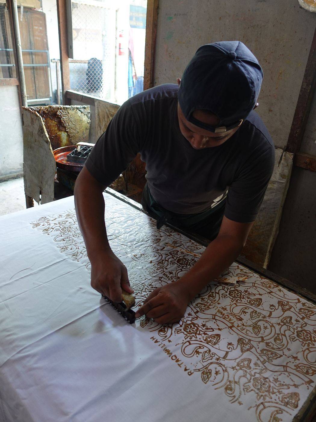 Proses penataan kain di meja produksi batik cap pabrik
