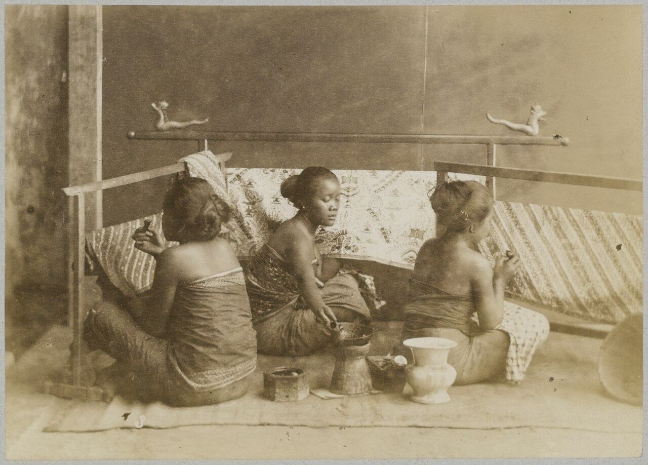 Tiga perajin wanita duduk di lantai mengerjakan kain batik di Yogyakarta, foto sekitar 1880